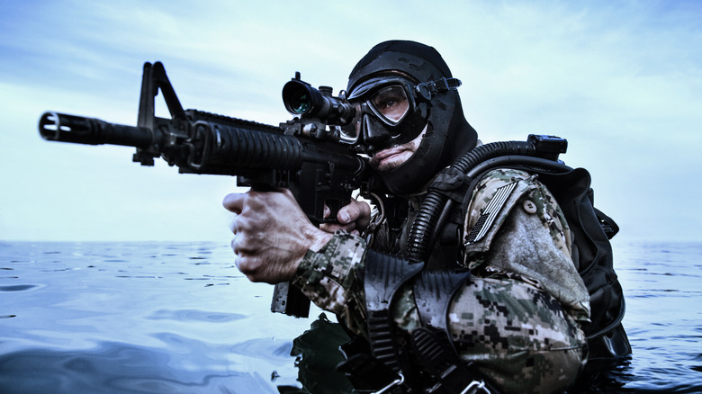 Navy SEAL wearing frogman gear in the water with gun at ready