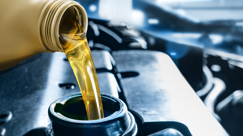 Pouring motor oil from plastic canister into a car engine
