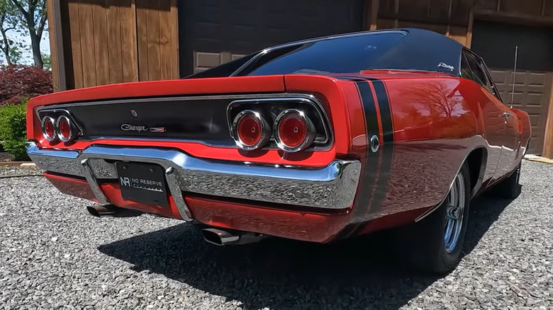 A red 1968 Dodge Charger R/T restomod parked on gravel