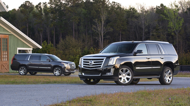 Black 2015 Escalade and Escalade ESV parked at farm.