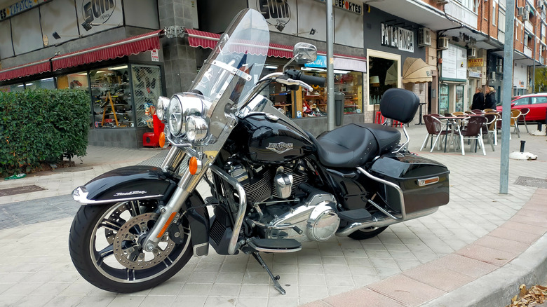 Black Harley Davidson Road King parked outside on sidewalk In front of shops