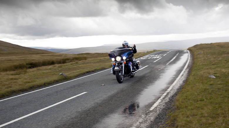 Man riding Harley Davidson Road King on an empty 2 lane road outside the city