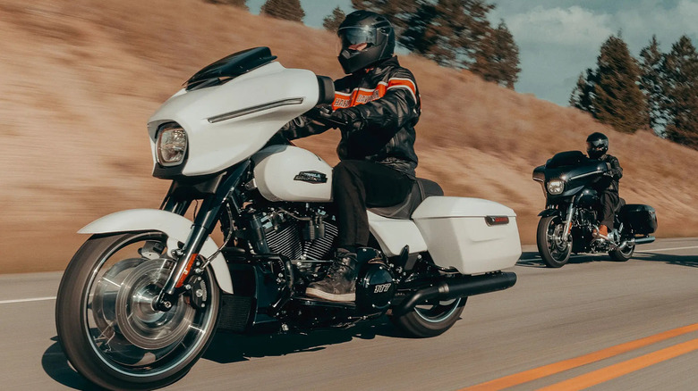 Two bikers ride down a highway on a black and a white Street Glide