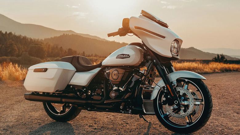 A white Street Glide parked next to a hilly forest in the afternoon