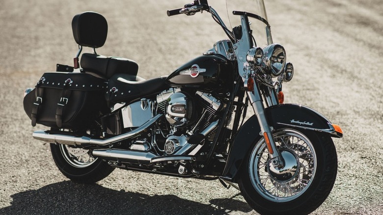 A black and chrome Heritage Softail Classic parked in the middle of a road on a sunny day