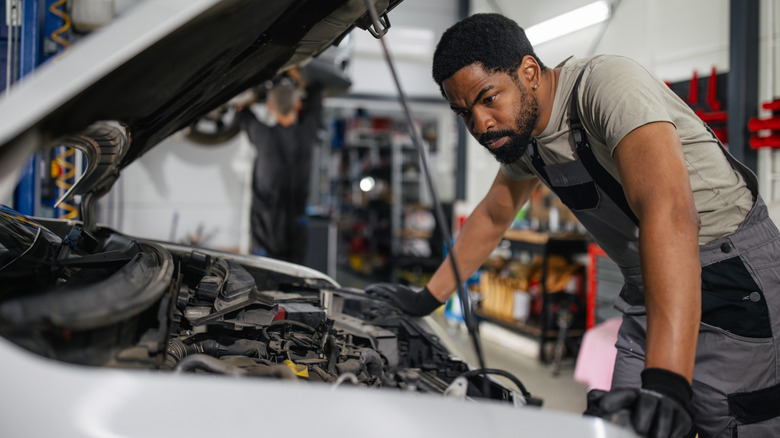A man inspecting the engine in his car