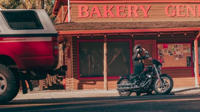 Rider mounting Softail Standard in front of store