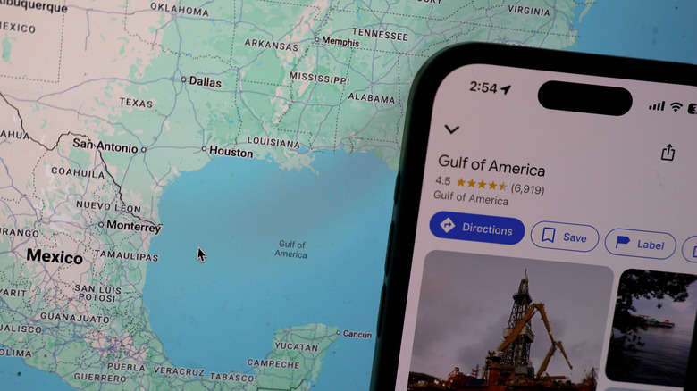 an iPhone running Google Maps showing Gulf of America in front of a screen showing the map for US-Mexico border