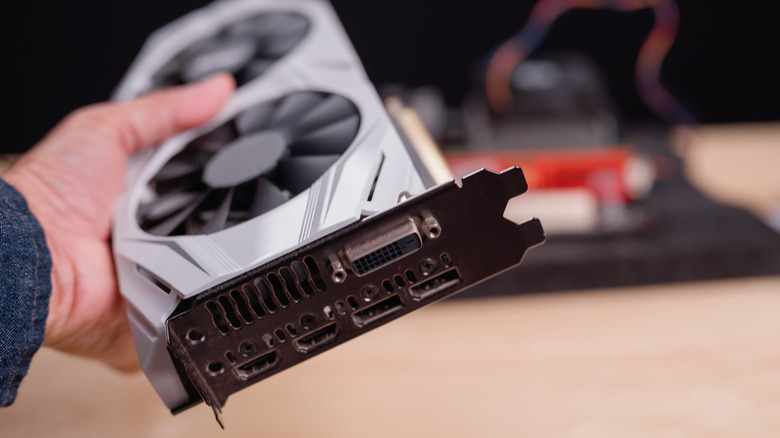 Hand holding up a GPU, showing the connection ports