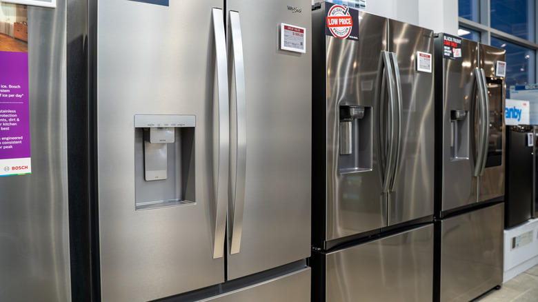 Close up of gray/silver stainless steel refrigerators in appliance store aisle