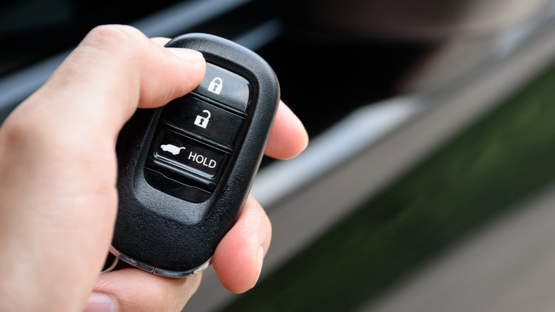 Person holding a key fob and pressing the lock button