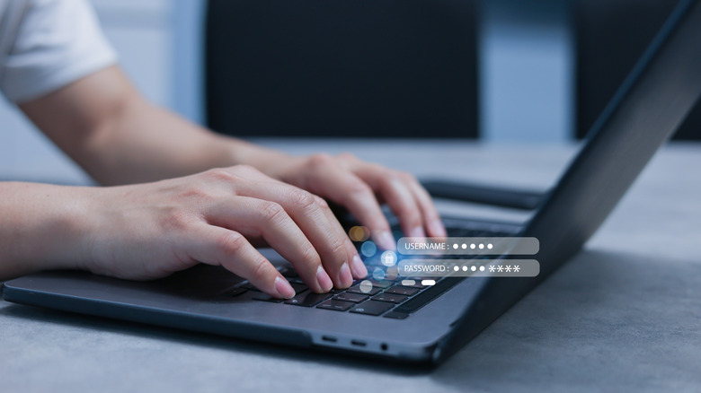 Person typing username and password on laptop