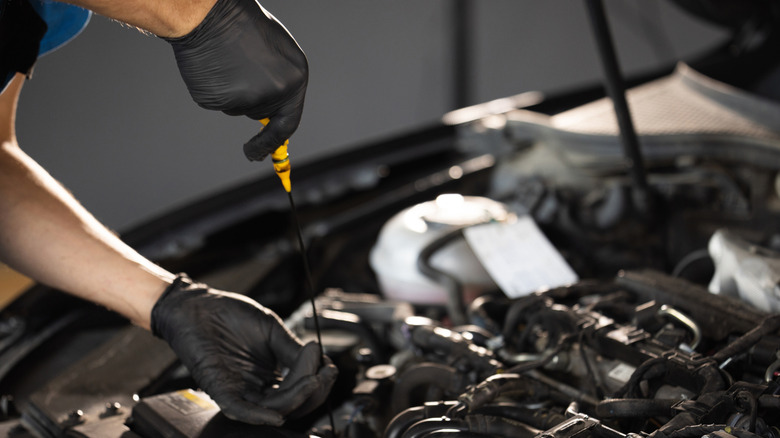 Close-up of automotive mechanic checks the oil level on the car engine dipstick