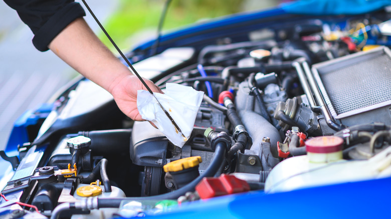 Person checking level of oil on a car engine dipstick