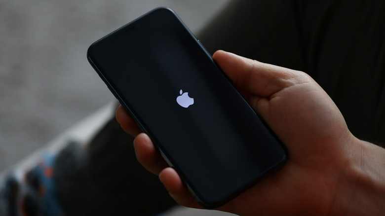 iPhone in hand showing the Apple logo
