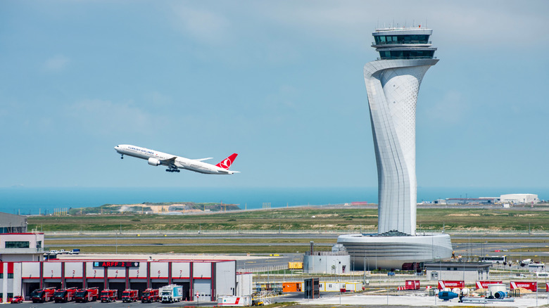 Air traffic control tower in front of a plane taking off