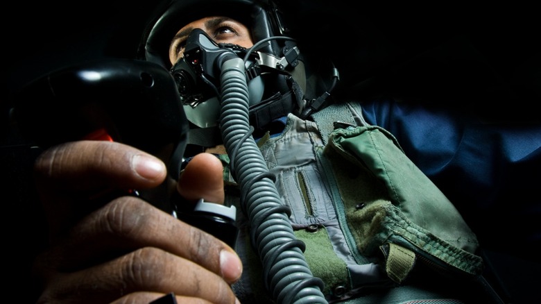 Air Force jet pilot holding control stick, wearing breathing mask