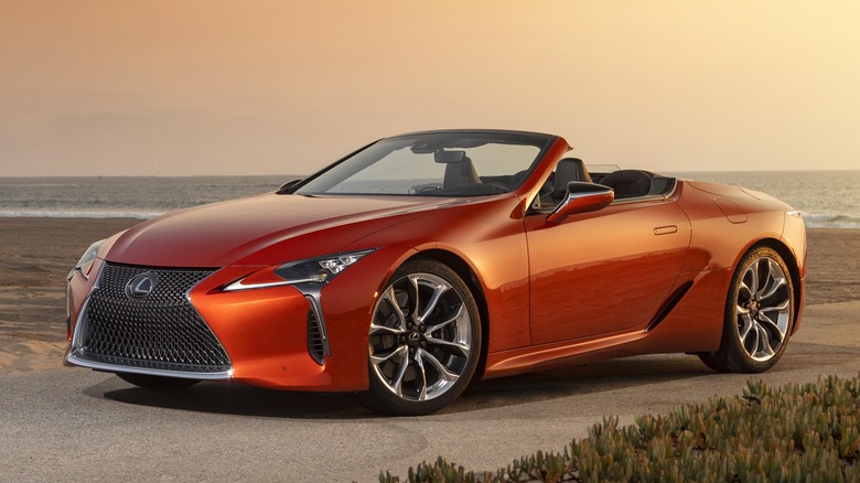 Front 3/4 view of orange Lexus LC Convertible parked at a beach
