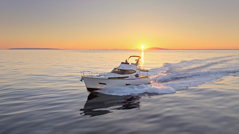 Boat cruising over open water while the sun sets in the background