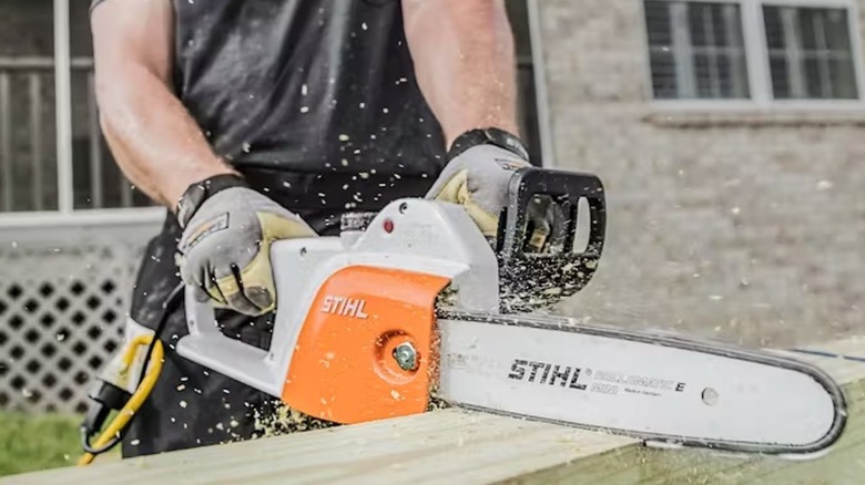 A Homeowner Using A STIHL Electric Corded Chainsaw To Cut Lumber