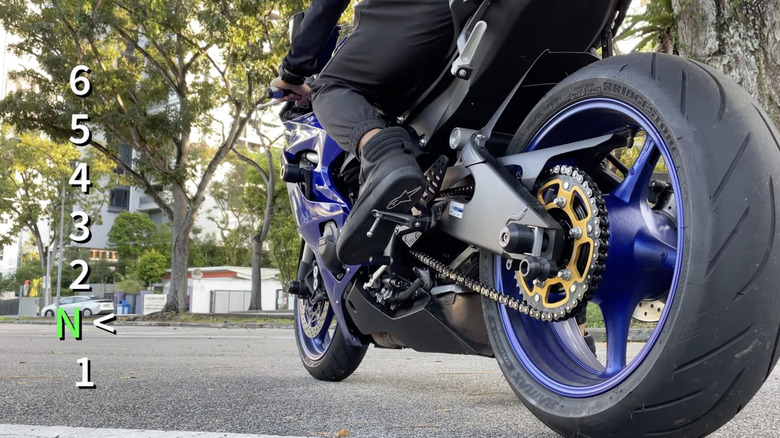 A man shifts to N on a blue motorcycle