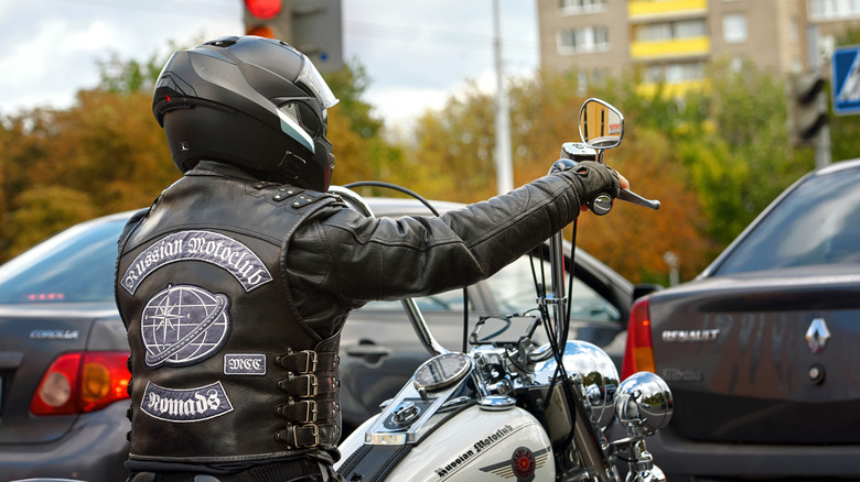 Biker in full leather gear with Russian motoclub patches waiting at an intersection on Harley Davidson motorcycle.