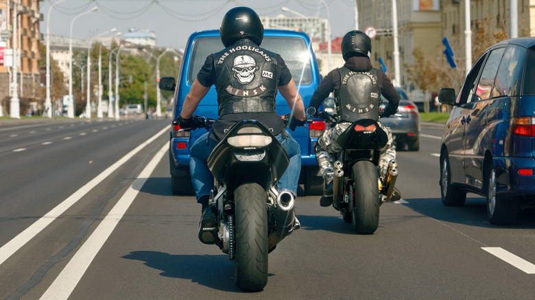 Two bikers from the Minsk Motorclub the Hooligans in leather vests and helmets ride motorcycles side by side through city traffic