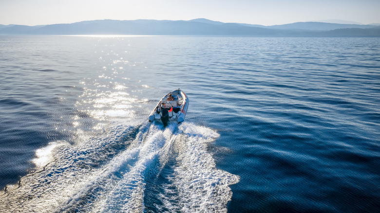 Small boat with outboard engine on the water with mountains in the distance