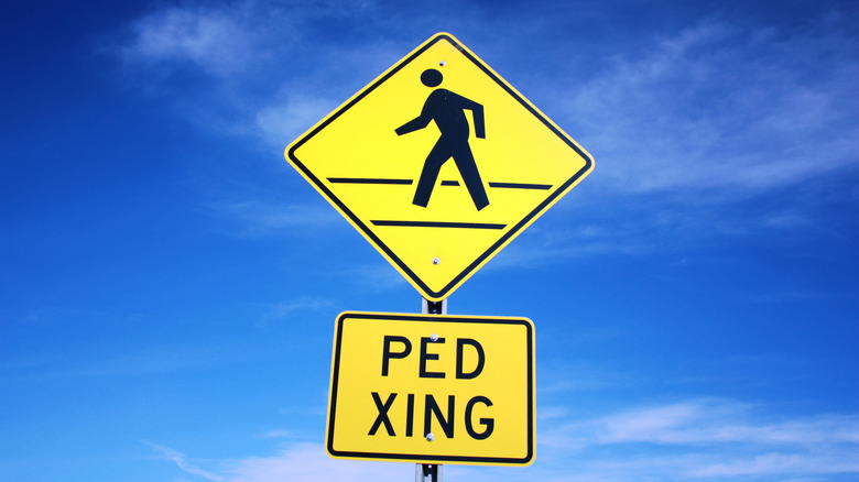 Pedestrian crossing sign against blue sky.