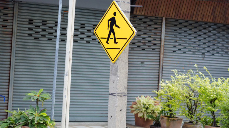 Alternate pedestrian crossing sign in front of closed businesses.