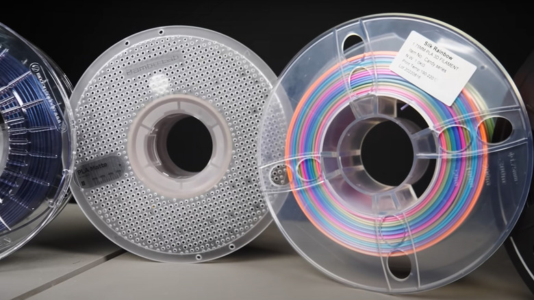 Three spools of PLA filament are lined up together, including a Silk Rainbow filament.