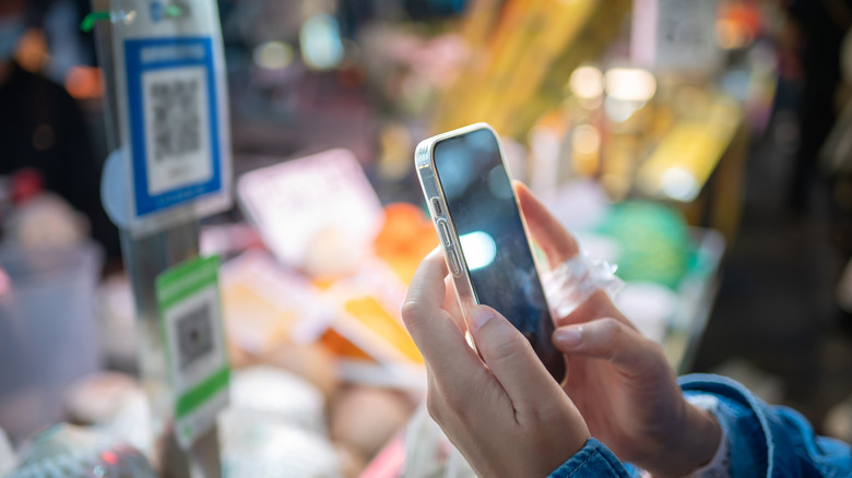 Close-up of a person scanning a QR code at a market stall