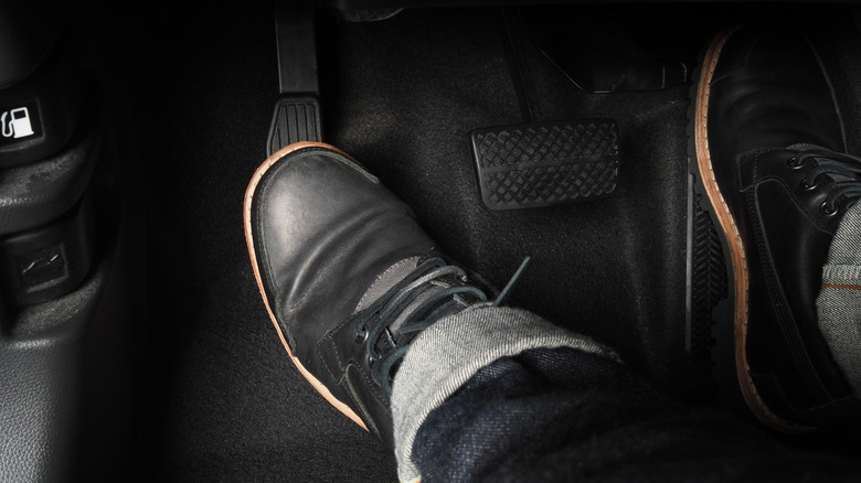 man with foot pressed down on clutch pedal