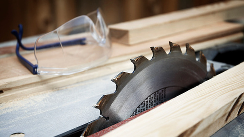 A table saw blade next to a pair of safety goggles.