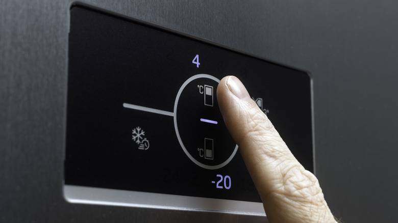 Close up of a refrigerator touch screen with a man's finger making adjustments.