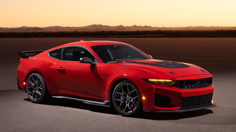 Front 3/4 view of red Ford Mustang Dark Horse SC on tarmac at dusk, lit from above