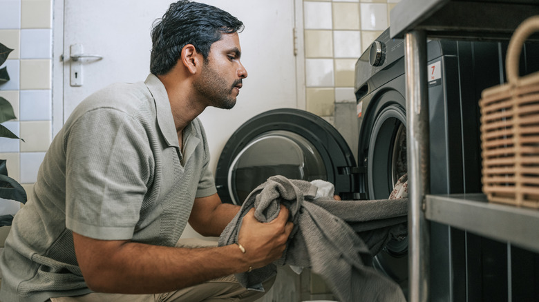 A man loading laundry into a front-loading washing machine