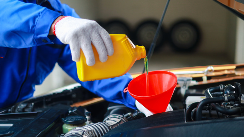 Mechanic pouring oil into vehicle.