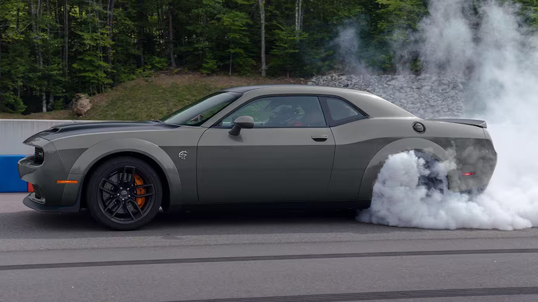 2023 Dodge Challenger SRT Hellcat performing burnout on drag strip, left-side view