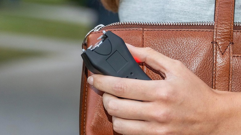 Person holding a stun gun close to purse