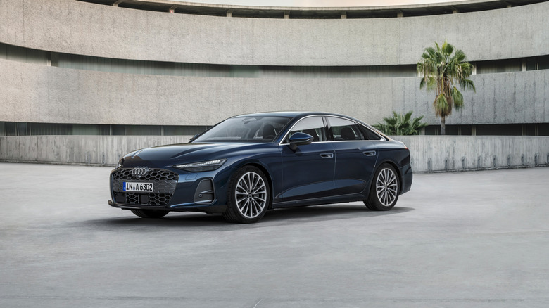 The new Audi A6 in dark blue, front 3/4 view, parking garage in the background