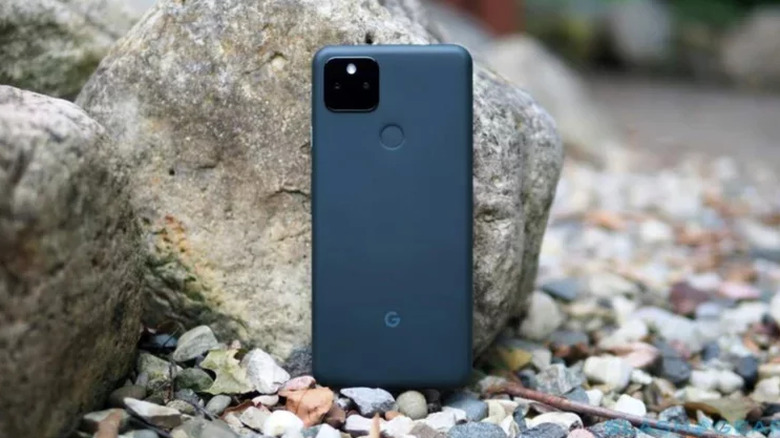 A Google Pixel 5a standing upright on small rocks