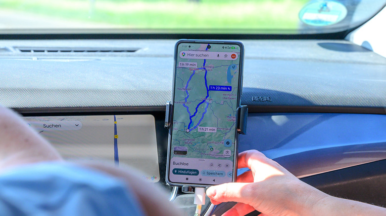 A person holding a phone with Google maps on its screen