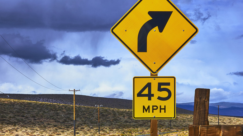 Curve warning sign on desert road with a 45 MPH speed limit warning underneath
