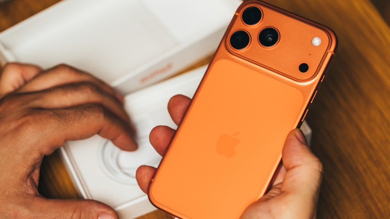 An orange iPhone 17 being unboxed.