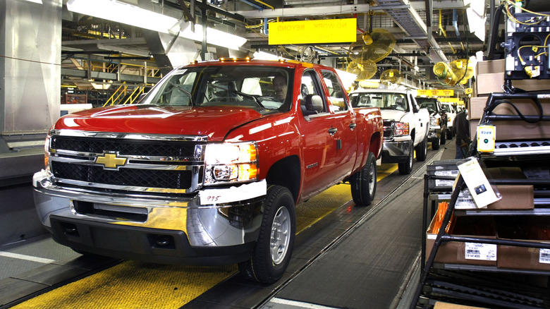 Front 3/4 view of red Chevrolet Silverado HD pickup on GM assembly line.