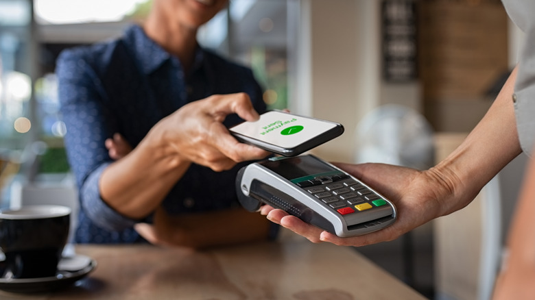 Person paying bill through smartphone using NFC technology