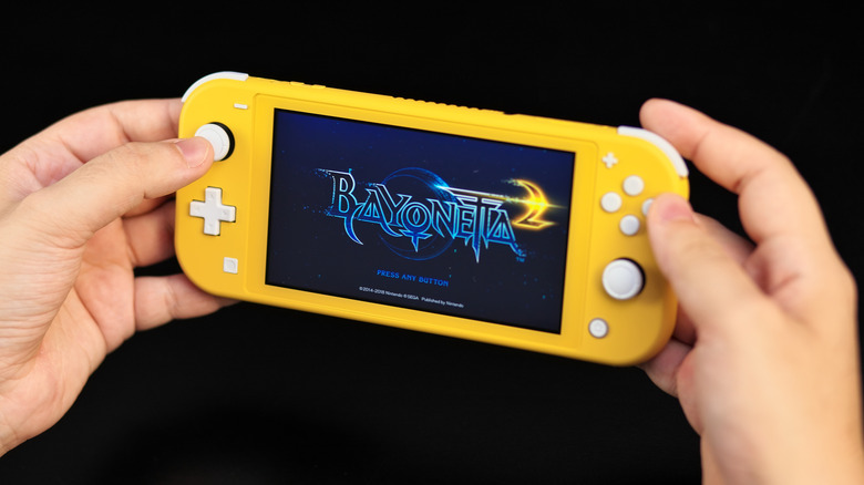 A yellow Switch Lite showing Bayonetta 2 onscreen.