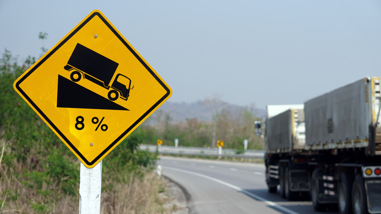 Semi truck passing a steep road gradient sign