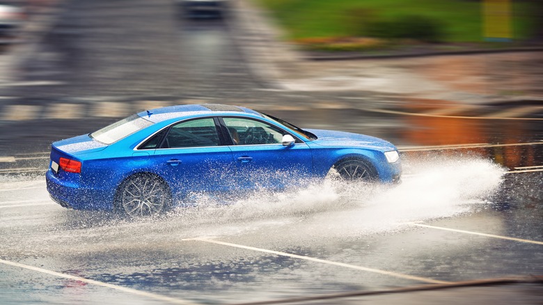 blue audi driving on a wet road